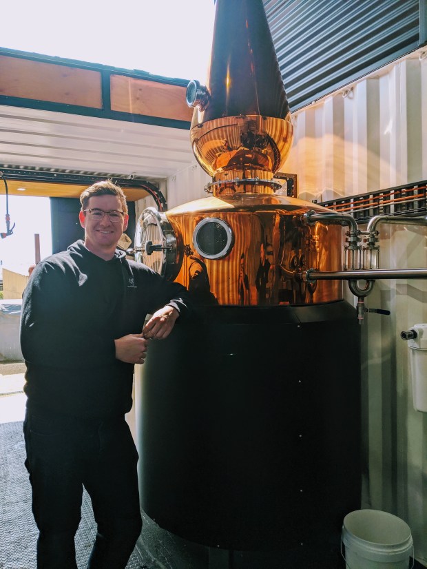 Tyler Clark of 7K Distillerty poses next to the still that he built